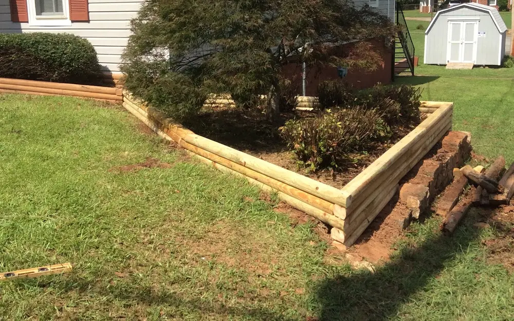 A mowed front lawn with a timber-edged planting bed beside a single-story home