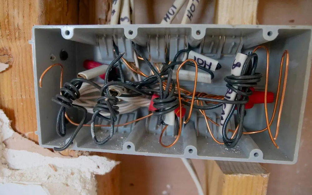 An opened wall box with its wiring exposed during a home electrical repair
